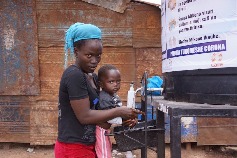 A mother and her child using one of ayiera initiative free hand washing stations